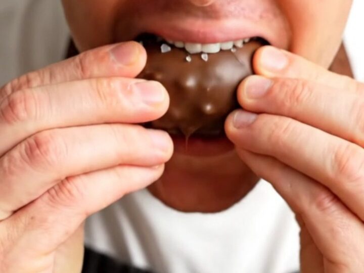 A chocolate-covered stuffed date snapped in half, showing the peanut butter and peanut filling.
