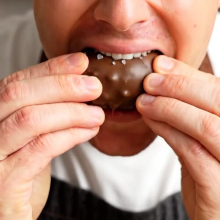 A chocolate-covered stuffed date snapped in half, showing the peanut butter and peanut filling.