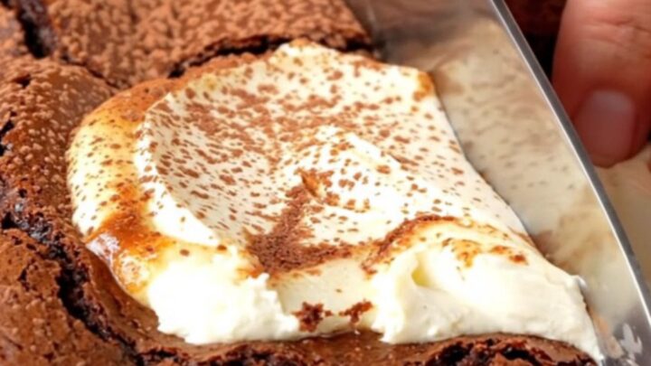 Brown butter cheesecake brownies with a creamy swirl, cut into squares on a parchment-lined pan.