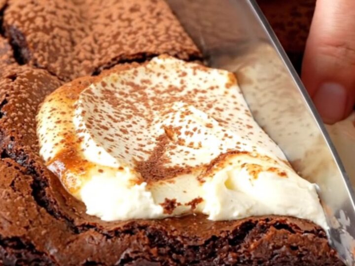 Brown butter cheesecake brownies with a creamy swirl, cut into squares on a parchment-lined pan.