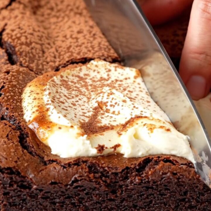Brown butter cheesecake brownies with a creamy swirl, cut into squares on a parchment-lined pan.