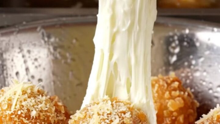 Golden fried potato cheese balls with a mozzarella pull on a rustic plate