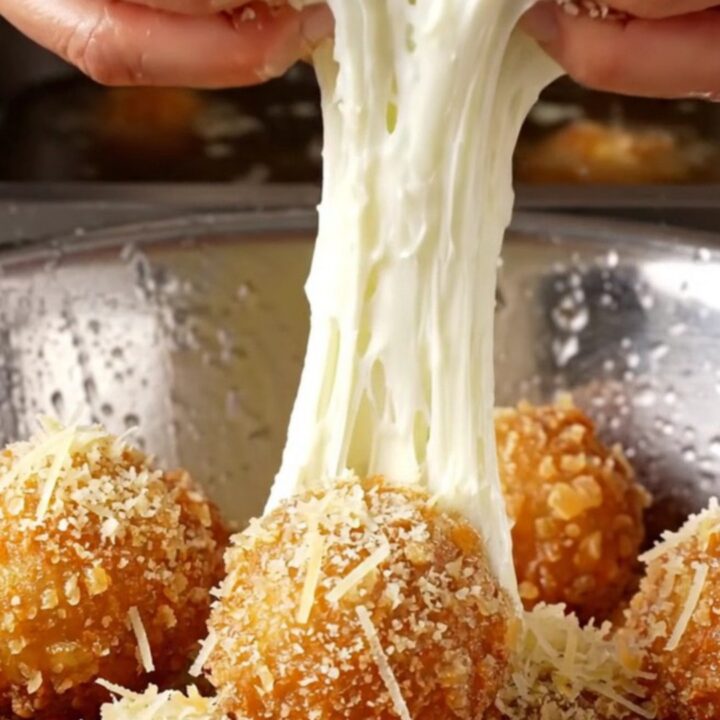 Golden fried potato cheese balls with a mozzarella pull on a rustic plate