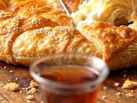 Golden, crispy skillet cheese börek sliced into wedges, showing layers of phyllo and melted feta, with parsley visible.