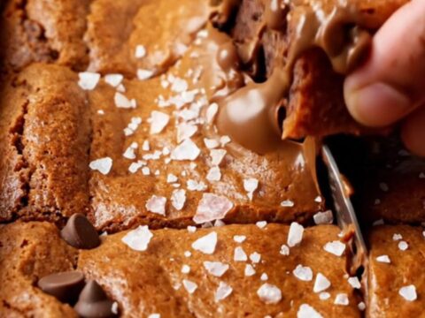 A stack of chewy brown sugar chocolate chip blondies with melted chocolate and flaky sea salt on top
