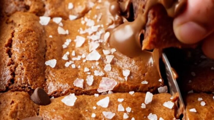 A stack of chewy brown sugar chocolate chip blondies with melted chocolate and flaky sea salt on top