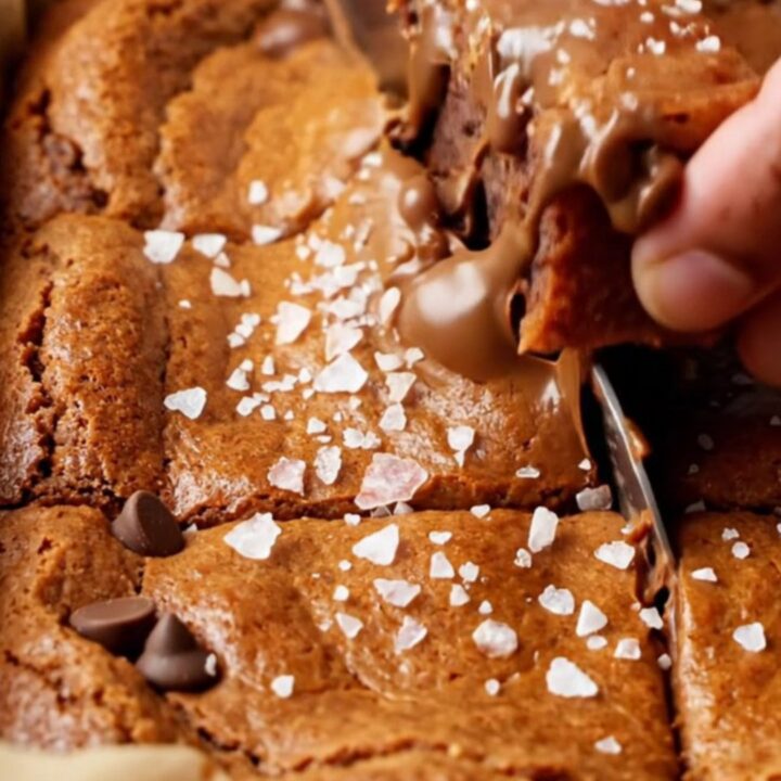 A stack of chewy brown sugar chocolate chip blondies with melted chocolate and flaky sea salt on top