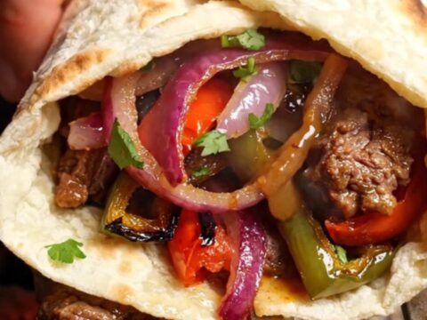 Crispy Turkish Adana kebab wrap sliced in half, showing juicy meat and colorful vegetables
