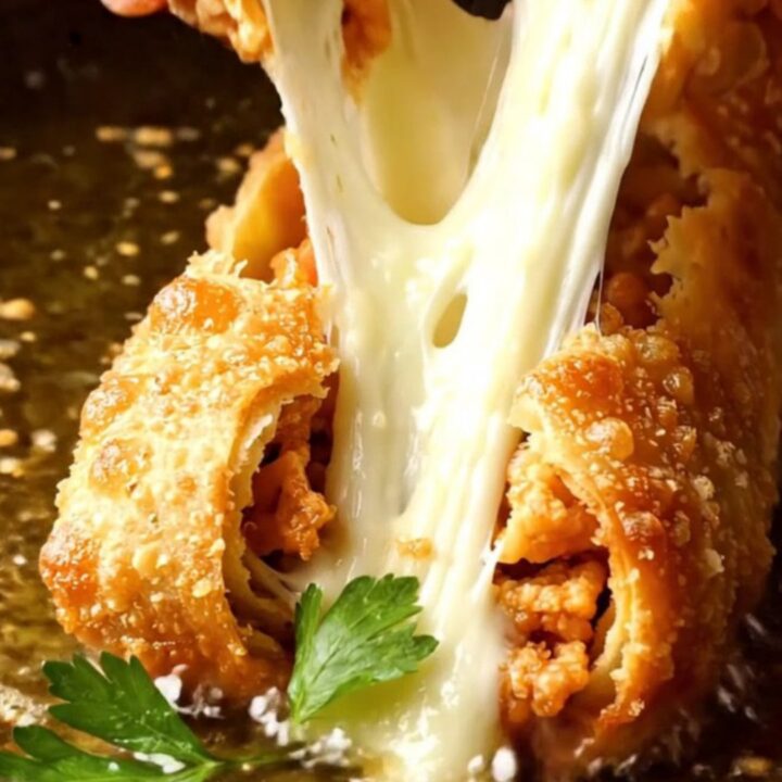 Crispy golden Paçanga Börek rolls on a platter, one broken open with melted cheese stretching.