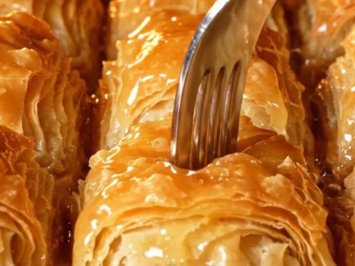 Golden mussel-shaped baklava with lemon syrup being poured over