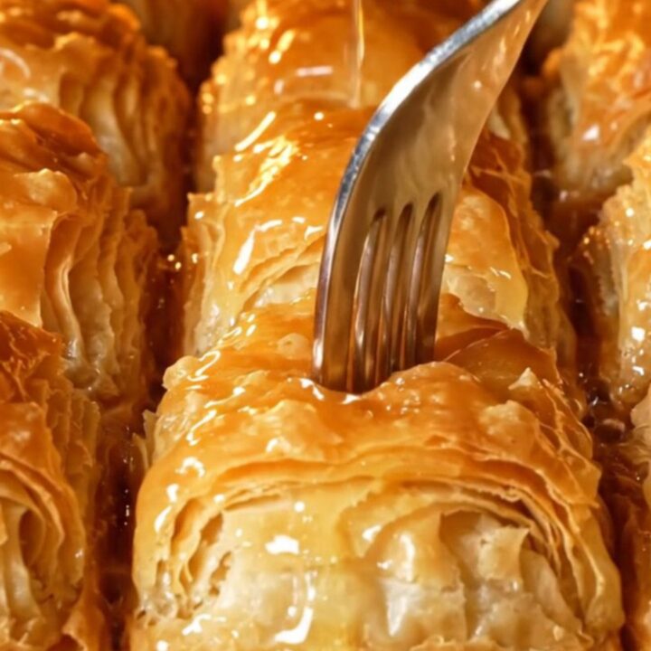 Golden mussel-shaped baklava with lemon syrup being poured over
