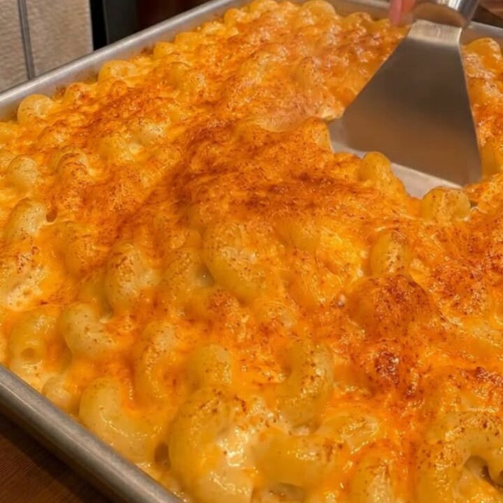 Plat à gratin de mac and cheese au cheddar doré, cuillère soulevant des cavatappi crémeux au fromage filant et à la vapeur