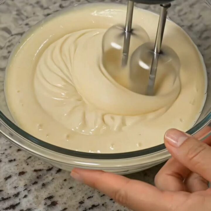 Bol en verre rempli de sauce crémeuse pour salade de fruits, épaisse et brillante, sur un plan de travail en granit