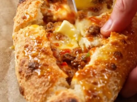 A golden, blistered Turkish pide cut into diagonal slices, showing juicy beef and melted cheese.