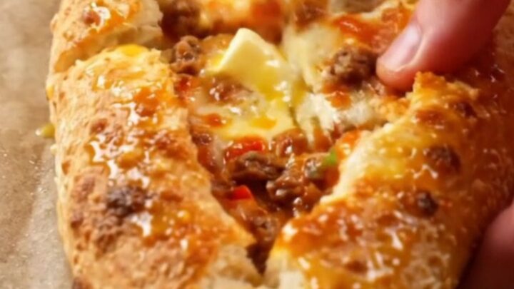 A golden, blistered Turkish pide cut into diagonal slices, showing juicy beef and melted cheese.