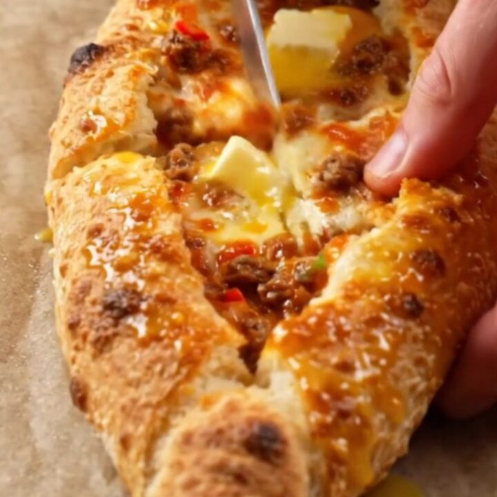 A golden, blistered Turkish pide cut into diagonal slices, showing juicy beef and melted cheese.