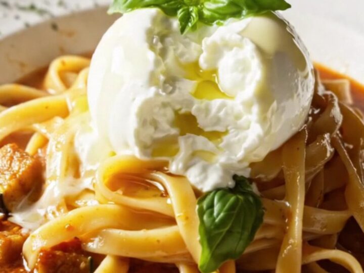 Fettuccine pasta in a roasted vegetable sauce topped with torn burrata and fresh basil