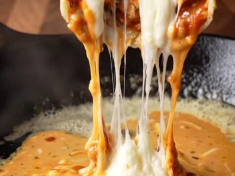 Crispy chipotle chicken wrap sliced in half, showing juicy chicken and melted cheese with creamy sauce on the side