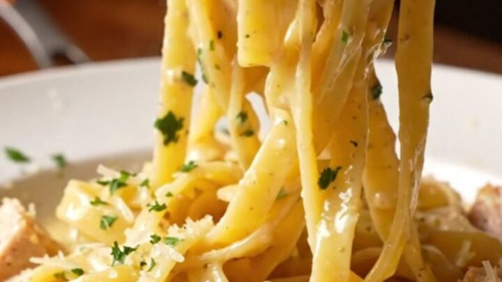 Creamy garlic parmesan chicken pasta in a skillet with a fork twirling fettuccine, topped with chicken and parsley.
