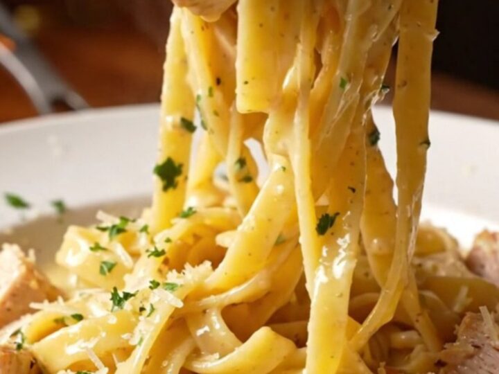 Creamy garlic parmesan chicken pasta in a skillet with a fork twirling fettuccine, topped with chicken and parsley.