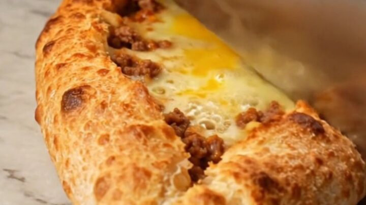 Sliced Turkish boat pide with spiced meat and melted cheese on a baking sheet
