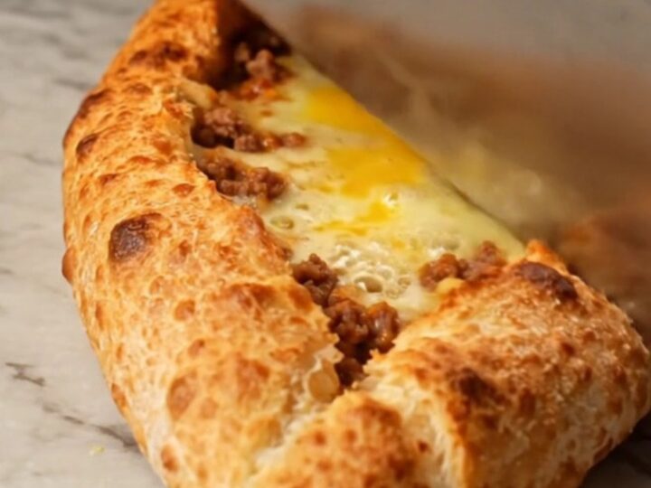Sliced Turkish boat pide with spiced meat and melted cheese on a baking sheet