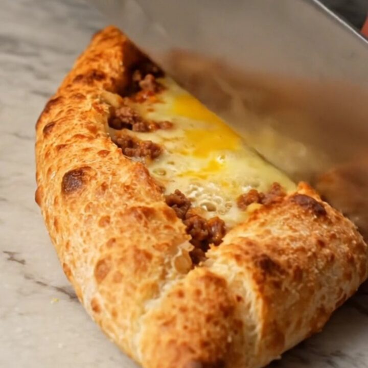 Sliced Turkish boat pide with spiced meat and melted cheese on a baking sheet