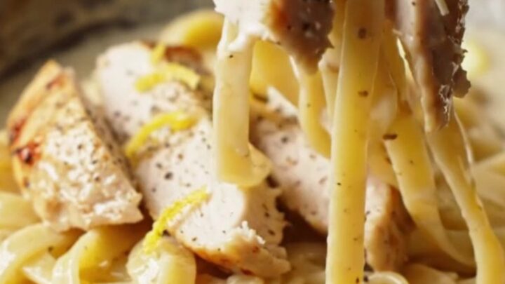 Twirled fettuccine with creamy lemon garlic sauce, topped with sliced chicken and parsley