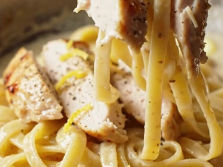 Twirled fettuccine with creamy lemon garlic sauce, topped with sliced chicken and parsley
