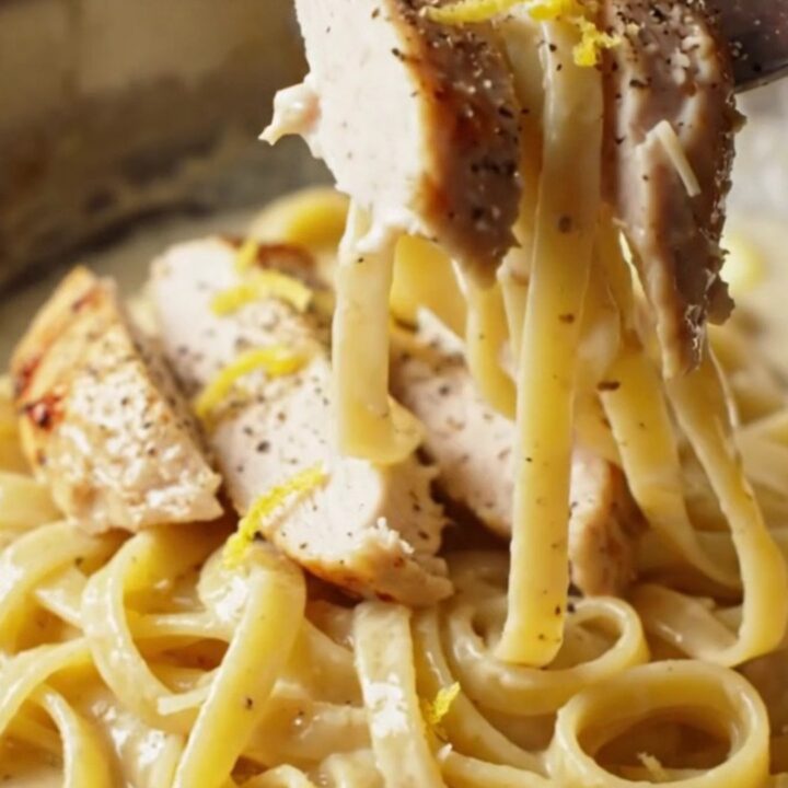 Twirled fettuccine with creamy lemon garlic sauce, topped with sliced chicken and parsley