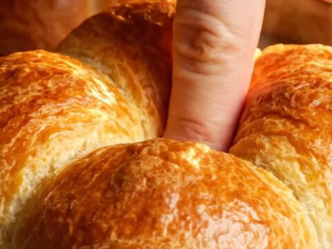 Golden flower-shaped brioche buns with chocolate filling, pulled apart on a baking sheet