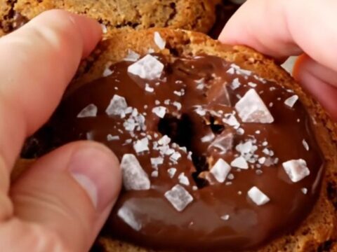 Giant bakery-style chocolate chip cookie being pulled apart, showing gooey melted chocolate center