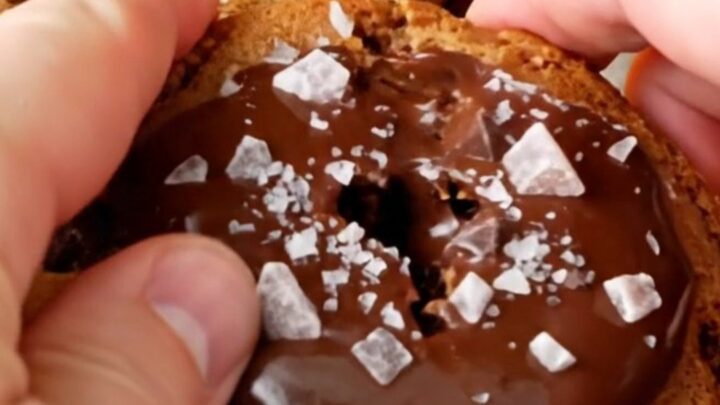 Giant bakery-style chocolate chip cookie being pulled apart, showing gooey melted chocolate center