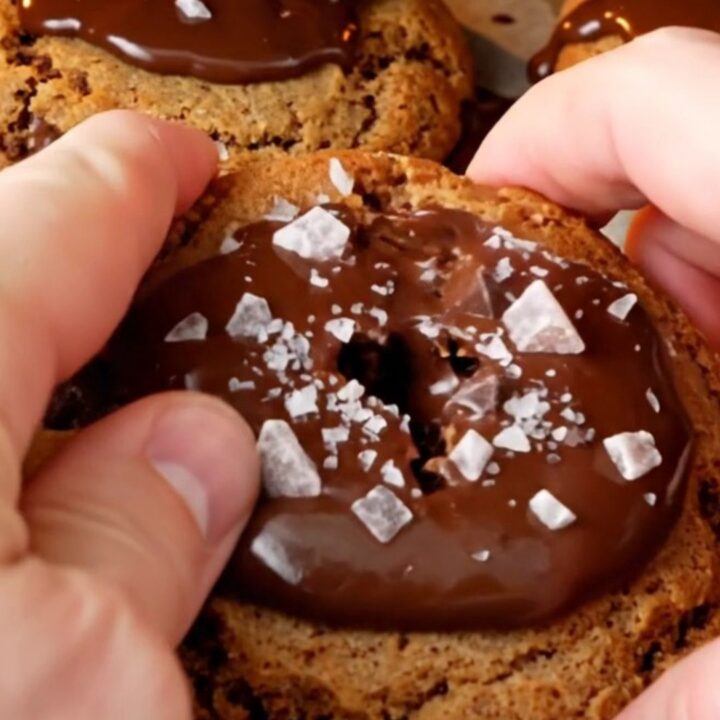 Giant bakery-style chocolate chip cookie being pulled apart, showing gooey melted chocolate center