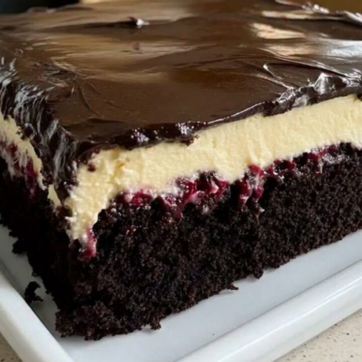 A beautifully layered Black Forest sheet cake on a white platter with visible chocolate sponge, cherry filling