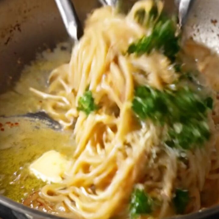 Twirled spaghetti coated in caramelized onion garlic butter sauce with parmesan and parsley