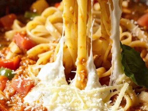 Tagliatelle pasta with roasted tomatoes and peppers, topped with melted mozzarella and basil