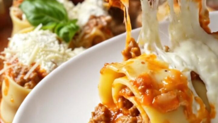 Skillet lasagna rollups with melted mozzarella and basil, lifted with a spatula