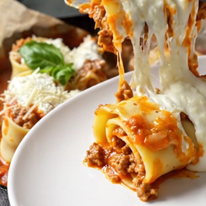 Skillet lasagna rollups with melted mozzarella and basil, lifted with a spatula