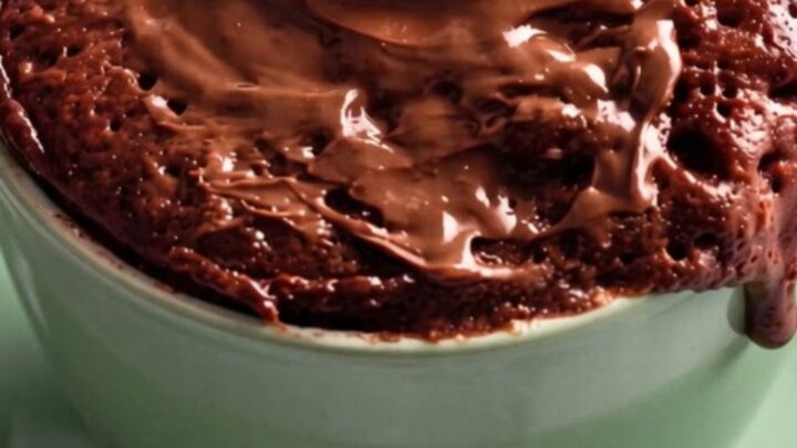 Gâteau au chocolat en mug vert menthe, nappage fondu coulant sur les parois, vapeur s'élevant du cœur moelleux