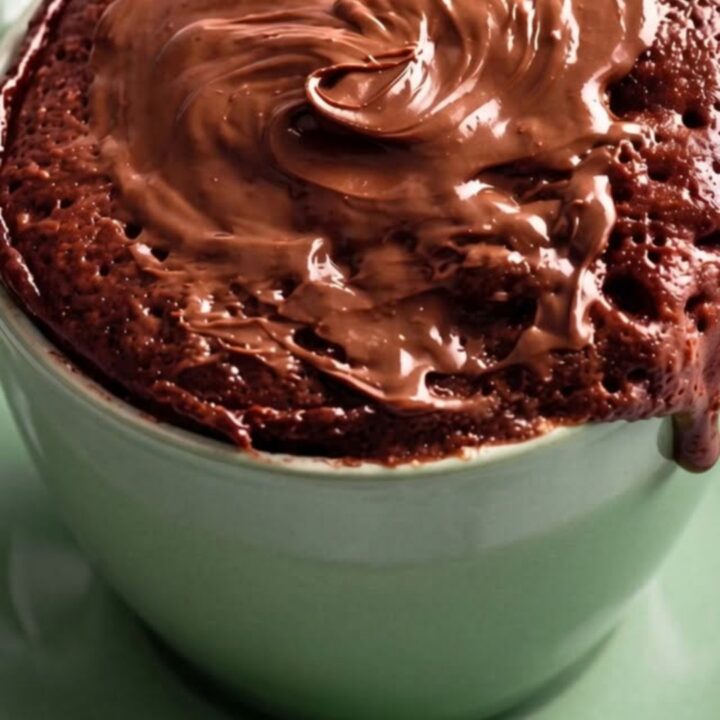 Gâteau au chocolat en mug vert menthe, nappage fondu coulant sur les parois, vapeur s'élevant du cœur moelleux