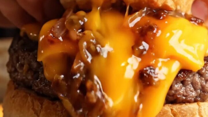 Sealed stuffed cheeseburger cut open showing melted cheese and juicy beef inside golden dough