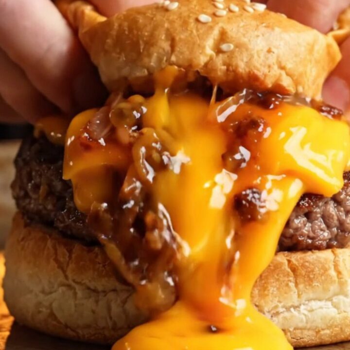 Sealed stuffed cheeseburger cut open showing melted cheese and juicy beef inside golden dough