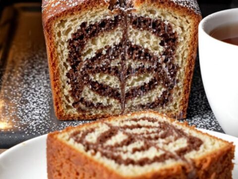 Classic butter marble cake loaf with zebra swirl, dusted with powdered sugar, on a wooden board.