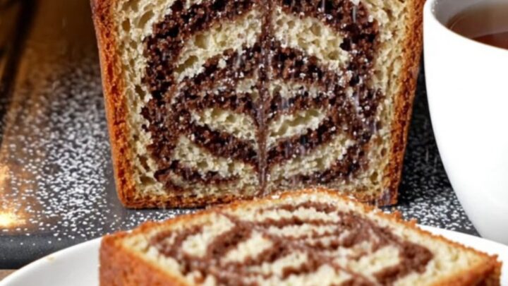 Classic butter marble cake loaf with zebra swirl, dusted with powdered sugar, on a wooden board.