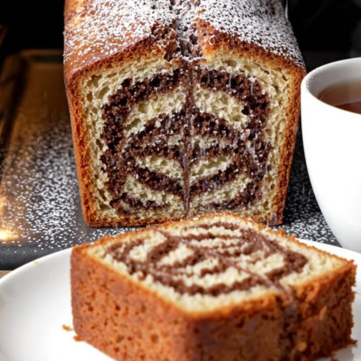 Classic butter marble cake loaf with zebra swirl, dusted with powdered sugar, on a wooden board.