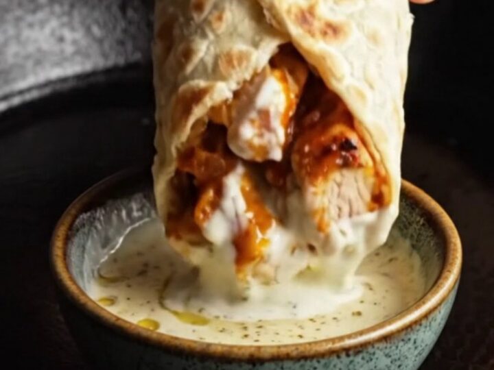 Sheet pan chicken kebab wraps cut in half, showing juicy chicken and charred peppers with garlic yogurt sauce.