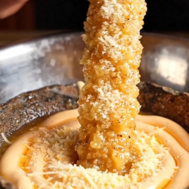 Giant golden crispy extra-long fries piled on a plate with a bowl of spicy mayo