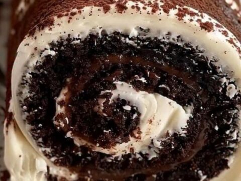 Roulé au chocolat au fudge et à la crème, saupoudré de cacao, sur un plat blanc