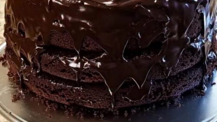 Gâteau au chocolat en trois couches sur un présentoir, ganache brillante coulant sur les bords